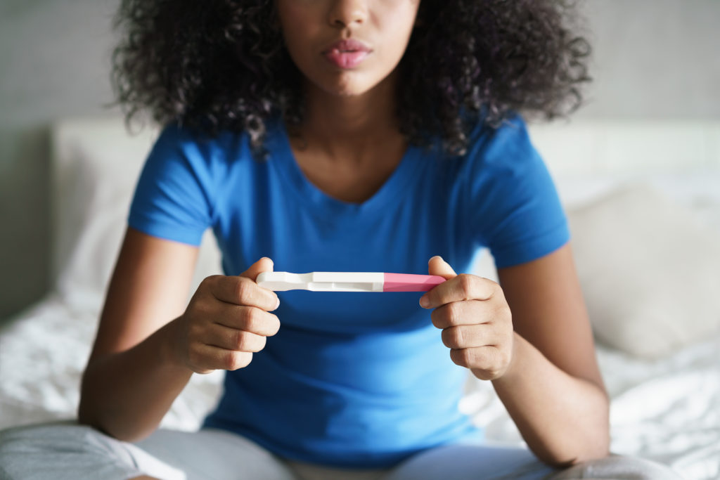 Disappointed hispanic girl getting unexpected result from pregnancy test kit. 